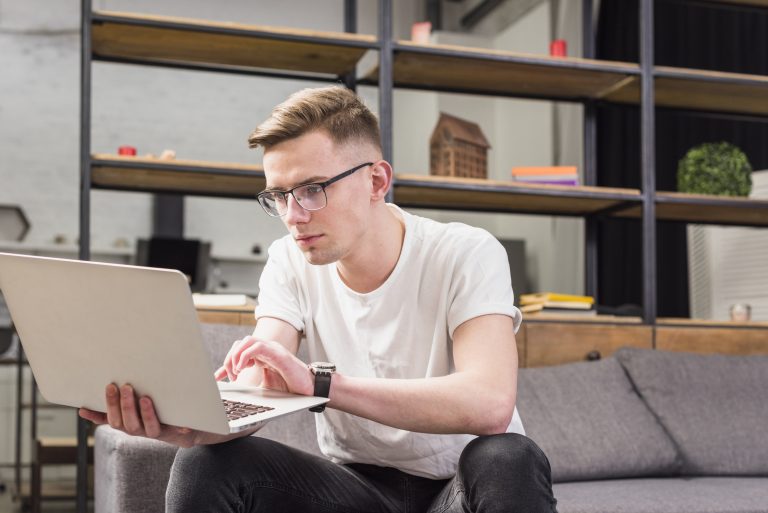 portrait-serious-young-man-sitting-sofa-using-laptop